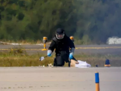 FILE PHOTO: A police officer in protective clothing works at Leipzig/Halle Airport in Schkeuditz, Germany, August 5, 2026, after the police said explosives experts examined a drone near a runway, and after a DHL cargo aircraft hit an unknown object as it was climbing away from the airport overnight, prompting an unscheduled landing in Hanover, according to a source familiar with the incident. REUTERS/Axel Schmidt/File Photo