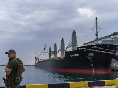 FILE - A security officer stands next to the ship Navi-Star which sits full of grain since Russia's invasion of Ukraine began five months ago as it waits to sail from the Odesa Sea Port, in Odesa, Ukraine, on July 29, 2022. Russia has repeatedly fired missiles and drones at Ukrainian ports key to sending grain to the world. Moscow has declared large swaths of the Black Sea dangerous for shipping. (AP Photo/David Goldman, File)