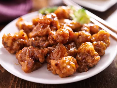 chinese orange chicken with chopsticks on round plate / Foto: Rez-art
