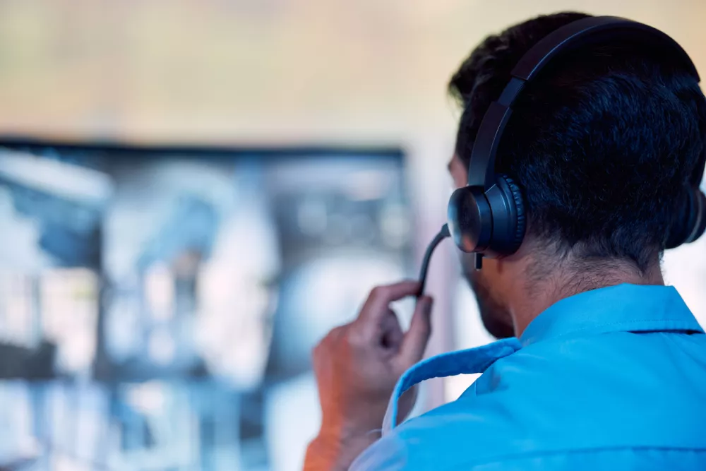 Police dispatch, communication headset and man talking, speaking and consulting with security, monitor CCTV or callcenter. Conversation, support consultation and back of person chat about 911 service / Foto: Jacob Wackerhausen Getty Images