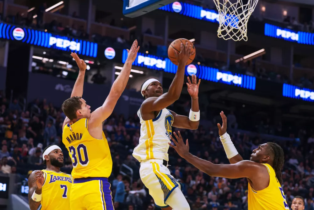 Golden State Warriors guard Brandon Williams (12) drives between Los Angeles Lakers guard Chris Ma&ntilde;on (30) and forward Kevon Looney (55) in the first period of a NBA pre-season basketball game in San Francisco Tuesday, Oct. 6, 2026. (Yalonda M. James/San Francisco Chronicle via AP)
