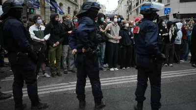 Police stand guard as students stand in front of a blockaded high school during a protest against under-resourced schools, in Paris, Wednesday, Oct. 7, 2026. (AP Photo/Thibault Camus)
