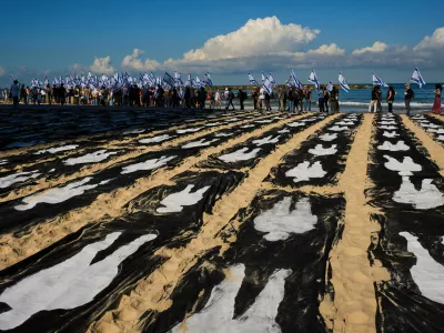 People carrying Israeli flags walk through an installation marking the third anniversary of the Oct. 7, 2023, Hamas attack on Israel, on the beachfront in Tel Aviv, Israel, Wednesday, Oct. 7, 2026. (AP Photo/Oded Balilty)