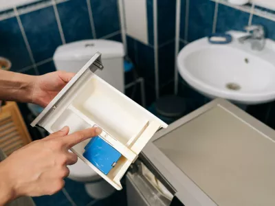 Human hand removing detergent dispenser drawer from washing machine for cleaning or maintenance, highlighting the importance of household appliance care and repairs.,Image: 1135405846, License: Royalty-free, Restrictions:, Model Release: yes 