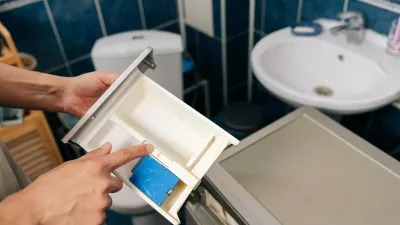Human hand removing detergent dispenser drawer from washing machine for cleaning or maintenance, highlighting the importance of household appliance care and repairs.,Image: 1135405846, License: Royalty-free, Restrictions:, Model Release: yes 