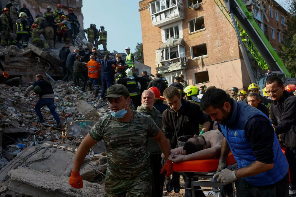 Emergency employees and volunteers carry a resident found under the debris at the site of an apartment building which was hit by a Russian missile strike in the town of Pryluky, amid Russia's attack on Ukraine, in the Chernihiv region, Ukraine, October 7, 2026. REUTERS/Valentyn Ogirenko