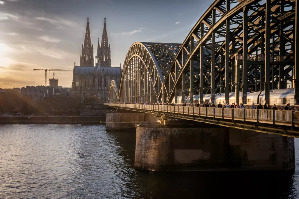 March 7, 2025. Cologne, Germany. View to the Cathedrale over the Rhine river with the Hohenzollern bridge. People are going on the bridge.