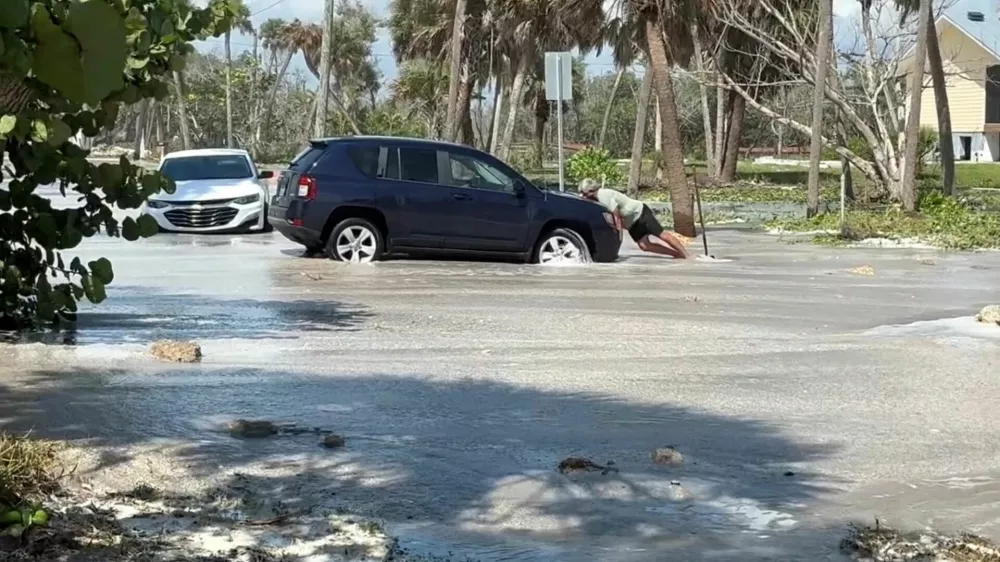 A man tries to push a car as waves wash over the road ahead of the arrival of Hurricane Isaias, in Englewood, Florida, US, October 9, 2026. Englewood Area Fire Control District via Facebook/Handout via REUTERS  THIS IMAGE HAS BEEN SUPPLIED BY A THIRD PARTY. NO RESALES. NO ARCHIVES. MANDATORY CREDIT. Verification lines: Buildings, electricity poles, road signs, road layout and trees matched file and satellite images in the area. Date verified by government reports of Manasota Key Road in Englewood, Florida was closed due to waves washing over road. The US National Hurricane Center said Hurricane Isaias made landfall in western Florida panhandle, warning of danger from storm surges and floods.