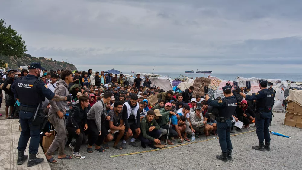 Migrants wait for food distribution to begin on El Trampol&iacute;n Beach in the Spanish enclave of Ceuta, Monday, Sept. 28, 2026. (AP Photo/Bernat Armangue)