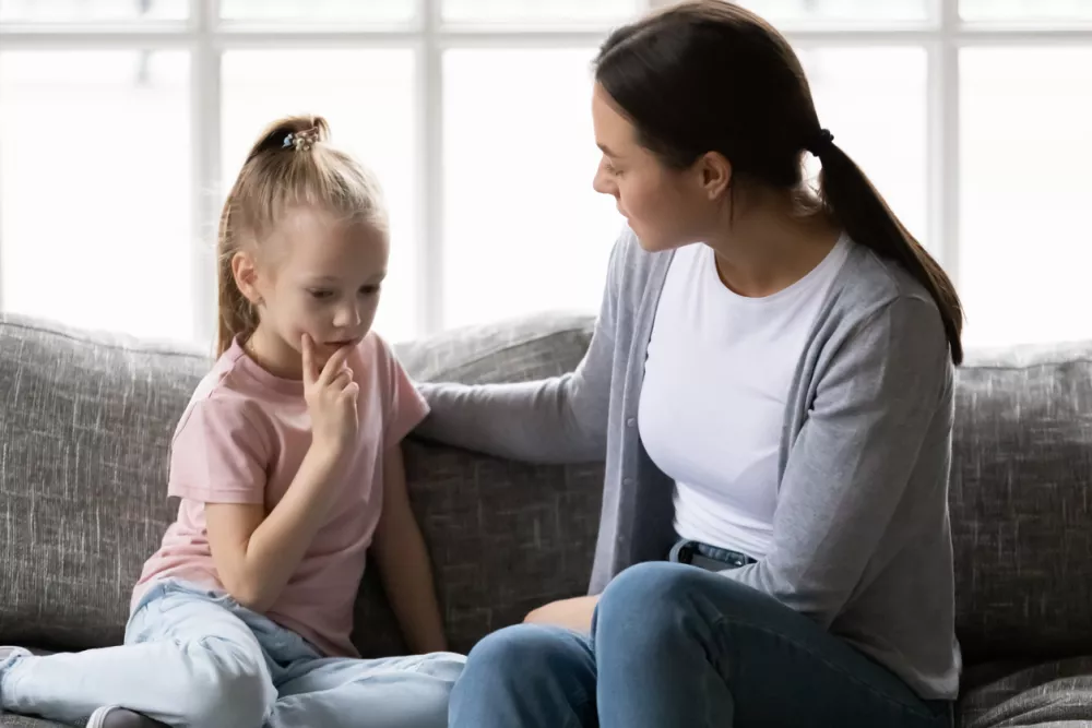 Serious mother talking to sad upset preschooler daughter kid at home. Mum consoling quiet girl, giving love, comfort, support, touching shoulder of child at home. Psychology, therapy, empathy concept