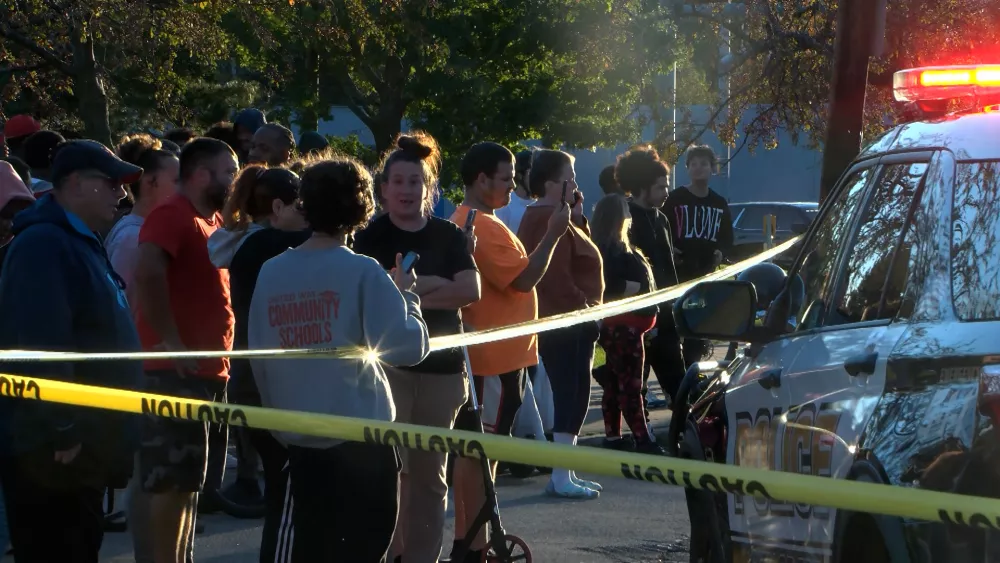 In this image from video provided by WJET, bystanders gather outside the scene of a shooting in Erie, Pa., on Friday evening, Oct. 9, 2026. (Matt Barnum/WJET via AP)