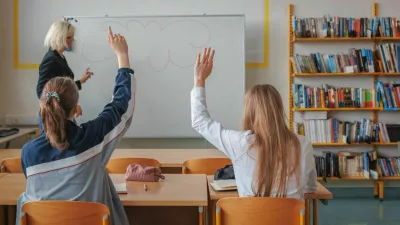 Two girl students during a classroom lecture, listening and communicating with a teacher. Education and learning concept.