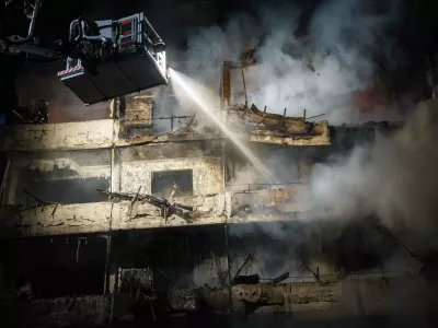 A rescue worker puts out a fire of a multi-story residential building damaged in a Russian missile strike on Kyiv, Ukraine, Wednesday, Oct. 14, 2026. (AP Photo/Evgeniy Maloletka)