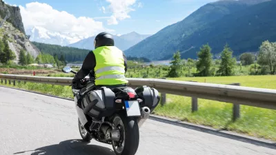 Motorbiker is riding his motorcycle on winding roads through the mountains in the summer sun