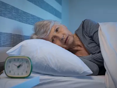 Worried senior woman in bed at night suffering from insomnia. Old woman lying in bed with open eyes. Mature woman unable to sleep at home.
