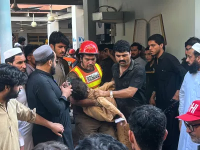 A rescue worker carries an injured child after rescuing him from the rubble of a roof collapse at a private school, in Peshawar, Pakistan, Thursday, Oct. 15, 2026. (AP Photo/Arif Khan)
