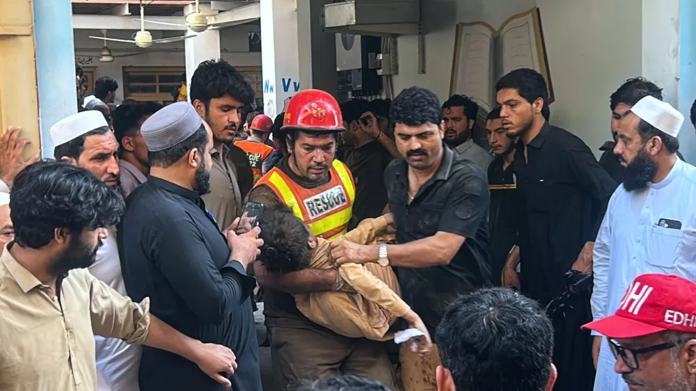 A rescue worker carries an injured child after rescuing him from the rubble of a roof collapse at a private school, in Peshawar, Pakistan, Thursday, Oct. 15, 2026. (AP Photo/Arif Khan)