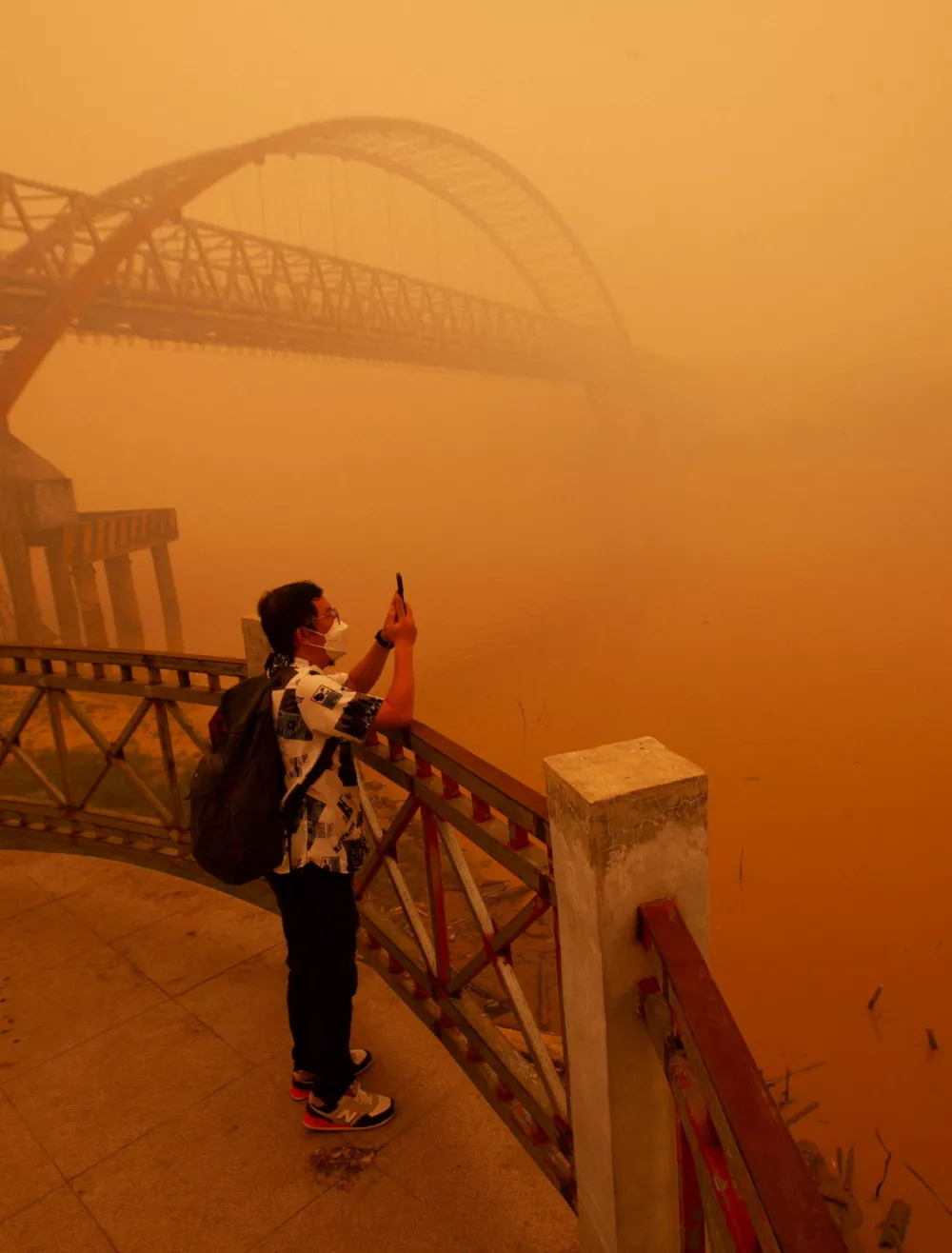 A man wearing a protective mask uses his smartphone to record the haze from wildfires that shrouds the area on the bank of the Kahayan River in Palangka Raya, Central Kalimantan province, Indonesia, October 14, 2026. REUTERS/Arief Rahman Septian Prathama