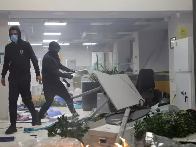 Hooded protesters vandalize a bank during clashes in Tirana, Albania, Wednesday, Oct. 14, 2026, as students joined the Flamingo anti-government movement. (AP Photo/Hameraldi Agolli)