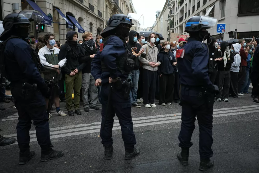 Police stand guard as students stand in front of a blockaded high school during a protest against under-resourced schools, in Paris, Wednesday, Oct. 7, 2026. (AP Photo/Thibault Camus)