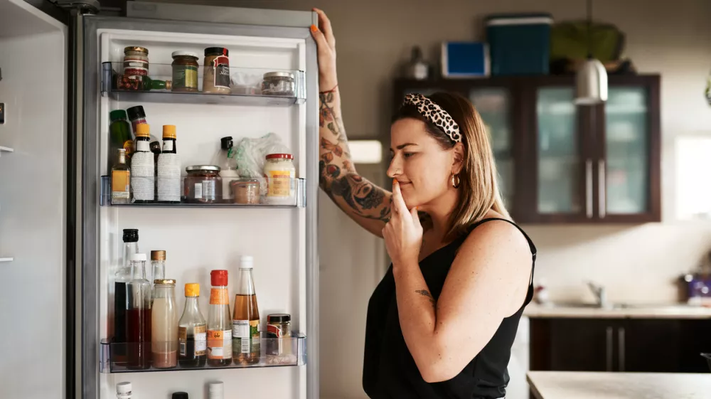 Shot of a young woman searching inside a refrigerator at home