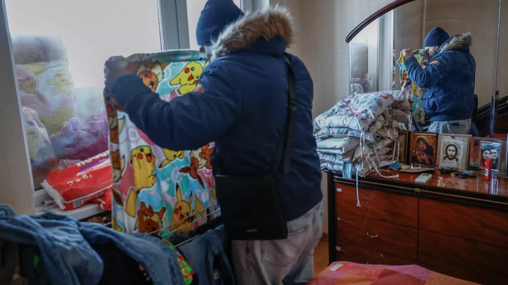 FILE PHOTO: Denys Davydenko, 40, hangs wet laundry at his family apartment, which has no heating or hot water and faces frequent power outages amid Russia's attack on Ukraine, in Kyiv, Ukraine, February 2, 2026. Waves of Russian attacks over the past four months left hundreds of thousands without electricity and water, making this the most devastating winter since the war started; and so the Davydenko family made the choice to stay at the family-owned Piggy Cafe Kyiv - with power supplied by a generator and heating. "Maksym likes it," Denys joked about their new reality. "He actually says that at home we have to do household chores. Now there's no dish-washing, cleaning, walking the dogs. So he is happy about that." REUTERS/Alina Smutko      SEARCH "SMUTKO COLD FAMILY" FOR THIS STORY. SEARCH "WIDER IMAGE" FOR ALL STORIES./File Photo