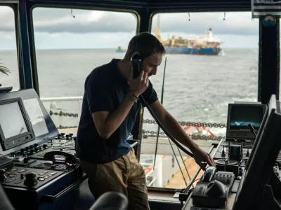Deck navigation officer on the navigation bridge. He speaks by VHF radio, GMDSS Watchkeeping, collision prevention at sea. COLREG / Foto: Igor-kardasov