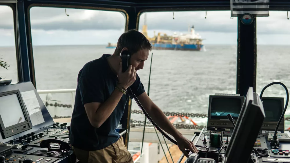 Deck navigation officer on the navigation bridge. He speaks by VHF radio, GMDSS Watchkeeping, collision prevention at sea. COLREG / Foto: Igor-kardasov