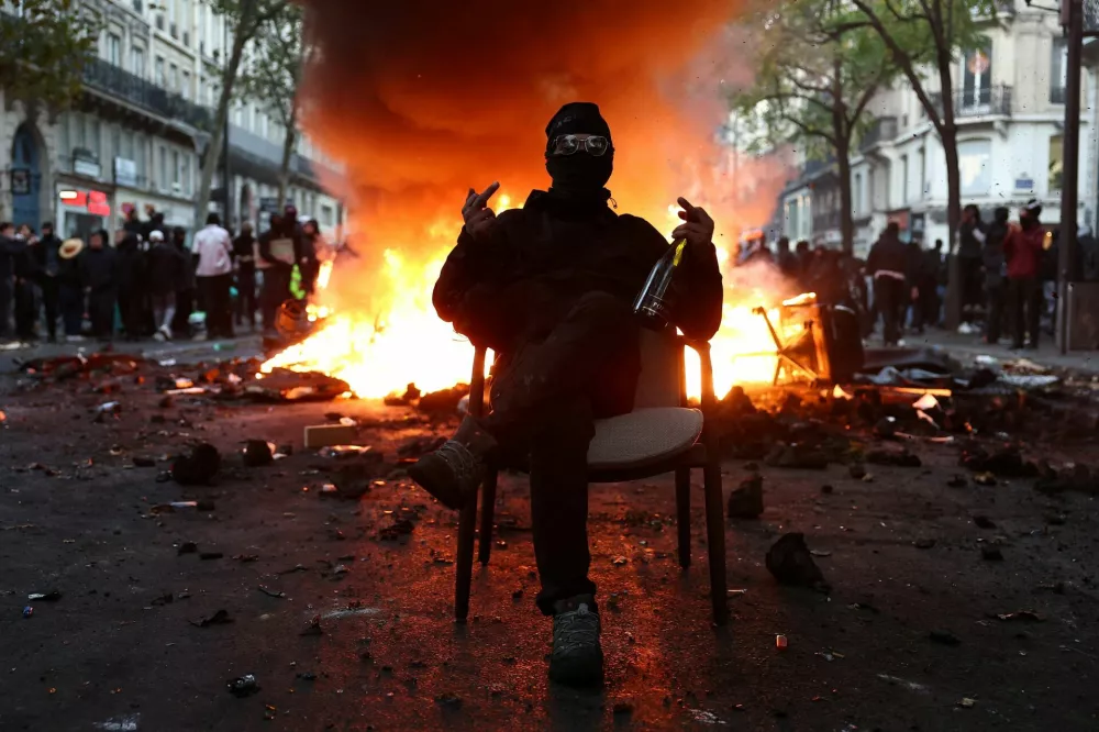 A masked protester sits on a chair in front of a burning barricade to block a street amid clashes during a day of demonstrations against the cost of living and rising fuel prices in Paris as part of nationwide protests called by the "Yellow Vests" movement, joined by French high school and university students, teachers and parents demanding better school conditions and government action, as well as labour unions, workers, farmers and retirees, France, October 17, 2026.  REUTERS/Abdul Saboor   TPX IMAGES OF THE DAY