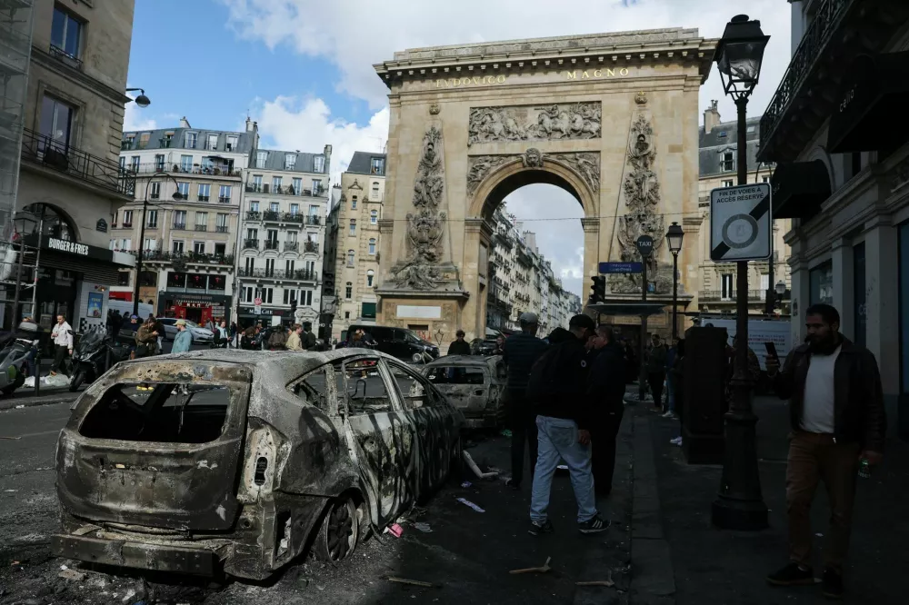 People inspect a destroyed vehicle, the day after clashes during a national day of demonstrations against the cost of living and rising fuel prices, in Paris, France, October 18, 2026. REUTERS/Stephanie Lecocq