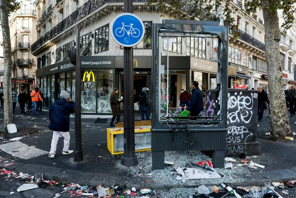 People walk past the damaged window of a McDonald's, the day after clashes during a national day of demonstrations against the cost of living and rising fuel prices, in Paris, France, October 18, 2026. REUTERS/Benoit Tessier   TPX IMAGES OF THE DAY