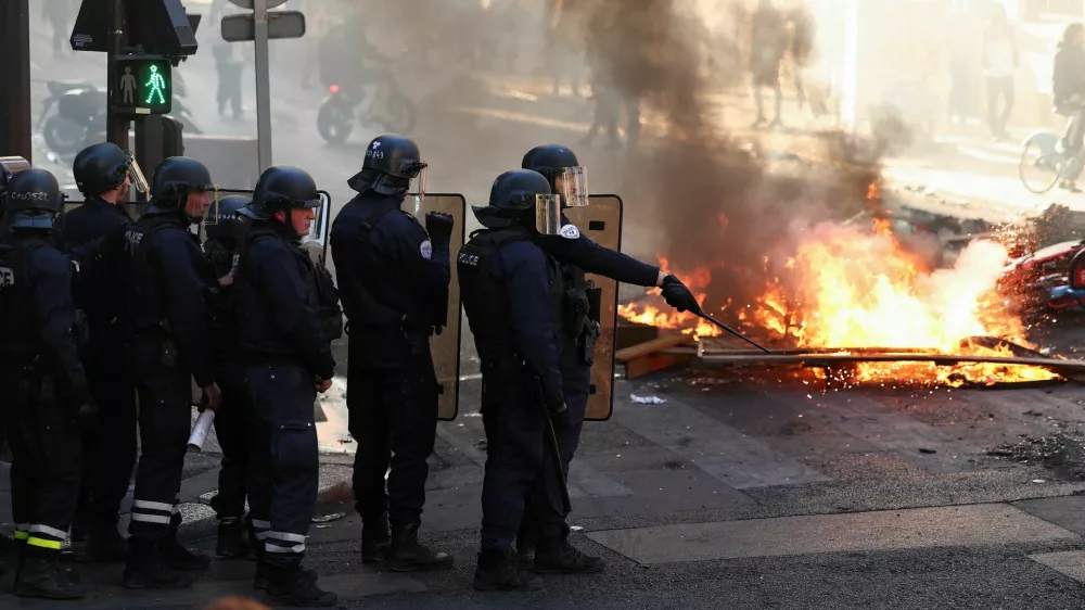 Francoski policisti stojijo zraven požara. 