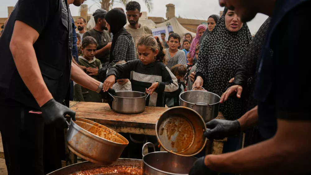 Palestinians receive food donated by the World Food Programme at a displacement camp in Deir al-Balah, in the central Gaza Strip, Sunday, Oct. 18, 2026. (AP Photo/Abdel Kareem Hana)