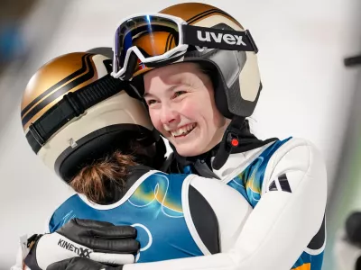 Silje Opseth, of Norway, right, hugs gold medalist Anna Odine Stroem, also of Norway, after the ski jumping women's large hill individual at the 2026 Winter Olympics, in Predazzo, Italy, Sunday, Feb. 15, 2026. (AP Photo/Matthias Schrader)