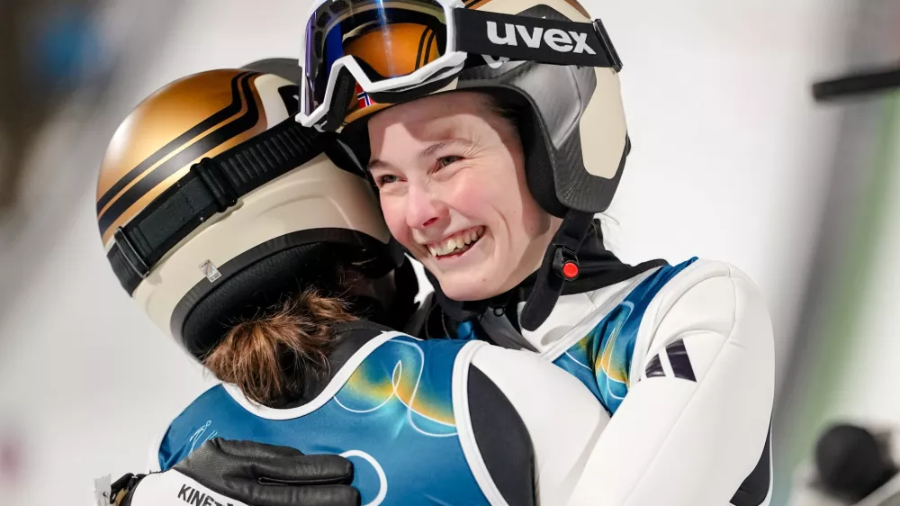 Silje Opseth, of Norway, right, hugs gold medalist Anna Odine Stroem, also of Norway, after the ski jumping women's large hill individual at the 2026 Winter Olympics, in Predazzo, Italy, Sunday, Feb. 15, 2026. (AP Photo/Matthias Schrader)