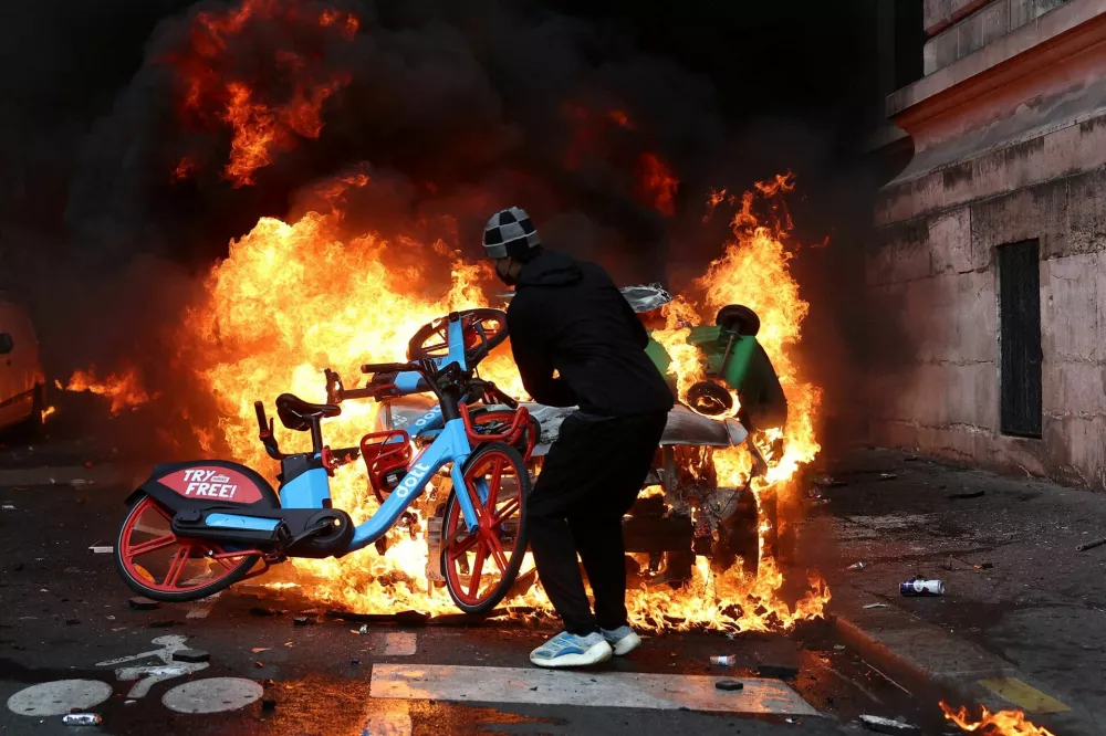FILE PHOTO: A protester throws a bicycle onto a burning car amid clashes during a day of demonstrations against the cost of living and rising fuel prices in Paris as part of nationwide protests called by the "Yellow Vests" movement, joined by French high school and university students, teachers and parents demanding better school conditions and government action, as well as labour unions, workers, farmers and retirees, France, October 17, 2026.  REUTERS/Abdul Saboor/File Photo