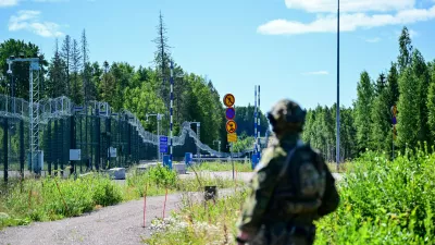 An officer from a special unit of the Finnish Border Guard stands in front of the border fence at a closed border crossing on the Finnish-Russian border.