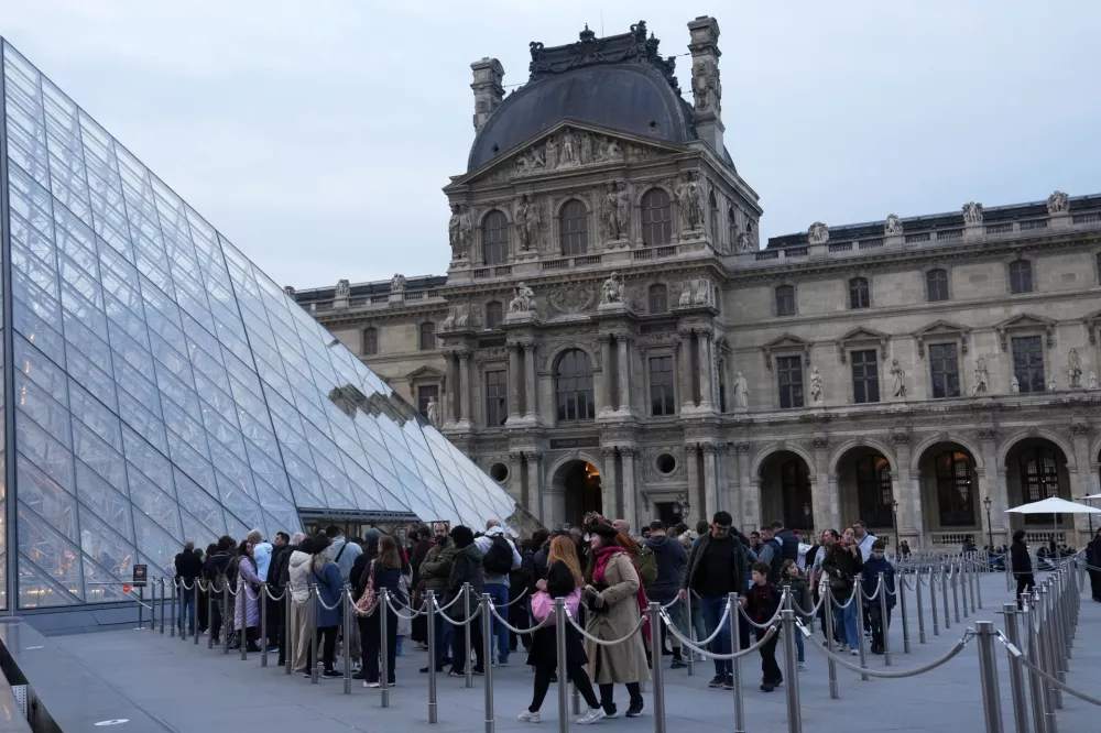 Visitors queue to enter the Louvre museum three days after historic jewels were stolen in a daring daylight heist, Wednesday, Oct. 22, 2025 in Paris. (AP Photo/Thibault Camus)