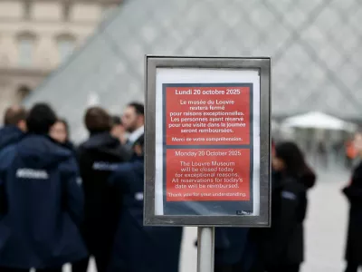 A placard which reads "The Louvre Museum will be closed today for exceptional reasons" is seen near the glass Pyramid of the Louvre Museum as the museum remains closed the day after a spectacular jewel heist by thieves who broke into the landmark by using a crane and smashing an upstairs window, stealing priceless jewelry from an area that houses the French crown jewels before escaping on motorbikes, in Paris, France, October 20, 2025. REUTERS/Benoit Tessier