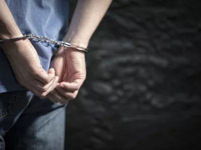 Arrested man in handcuffs with handcuffed hands behind back