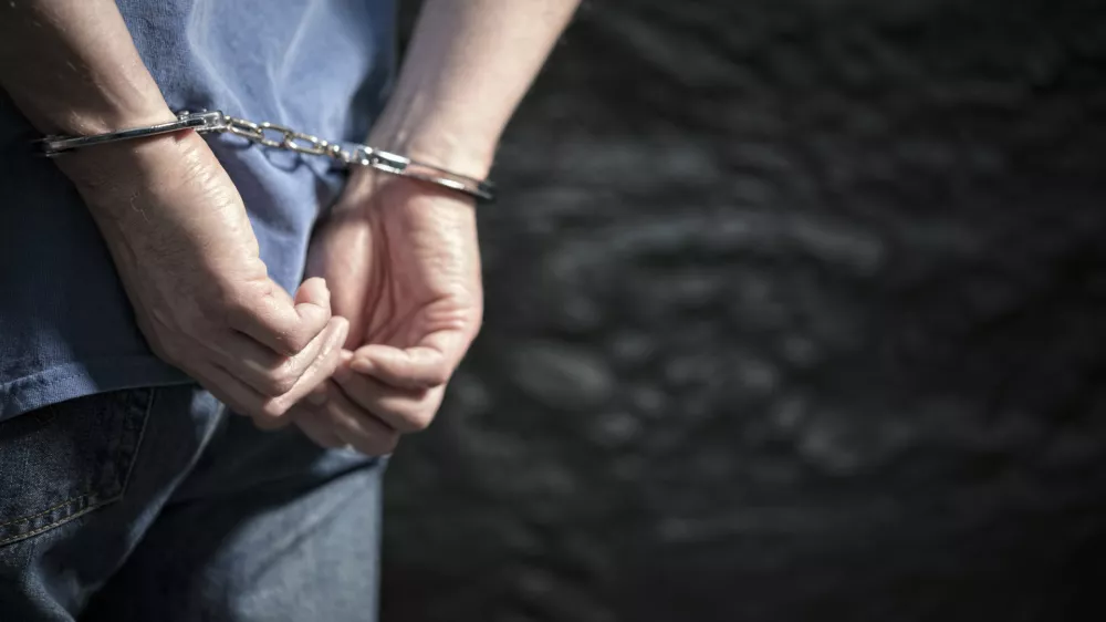 Arrested man in handcuffs with handcuffed hands behind back