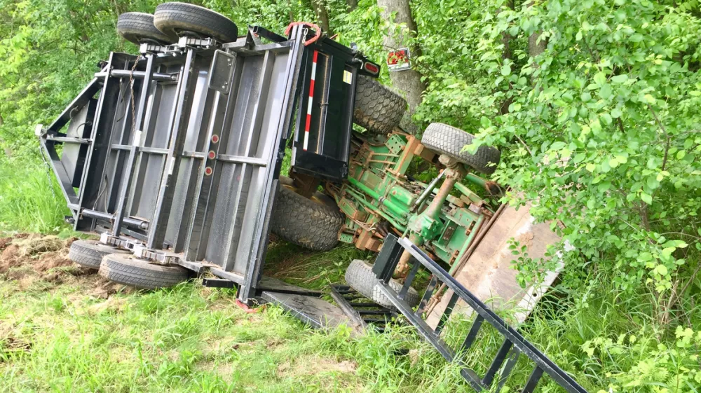 Overturned tractor and trailer laying in the ditch after an accident