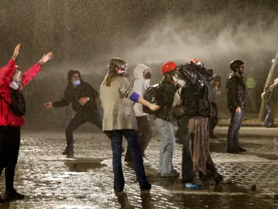 Anti-government protesters stand amid the spray from a police water canon in Tirana, Albania, late Tuesday, Oct. 20, 2026. (AP Photo/Boris Grdanoski)