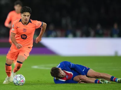 PSG's Khvicha Kvaratskhelia grimaces in pain after a challenges for the ball with Barcelona's Xavi Espart, left, during the Champions League opening phase soccer match between Paris Saint-Germain and FC Barcelona in Paris, Tuesday, Oct. 20, 2026. (AP Photo/Thibault Camus)