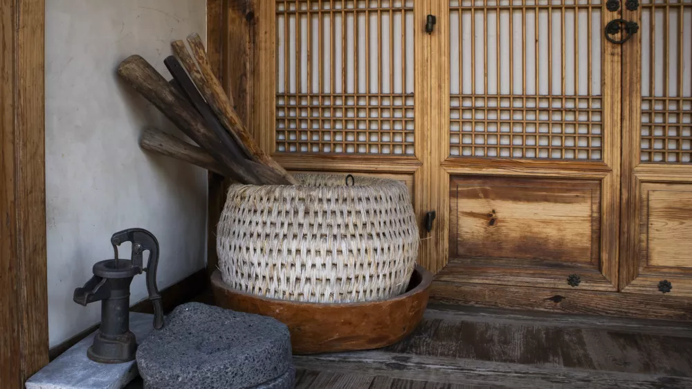 There are wooden baskets and wooden bowls on the floor of a Hanok house..