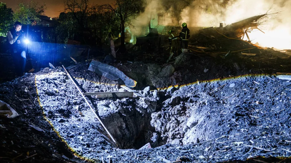 A journalist films a crater after a Russian missile strike on residential neighbourhood in Kyiv, Ukraine, Wednesday, Oct. 21, 2026. (AP Photo/Evgeniy Maloletka)