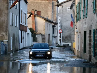 A car drives through a flooded street of Saint-Germain de Confolens as severe flooding hits western France amid storm Nils, Thursday, Feb. 12, 2026. (AP Photo/Yohan Bonnet)