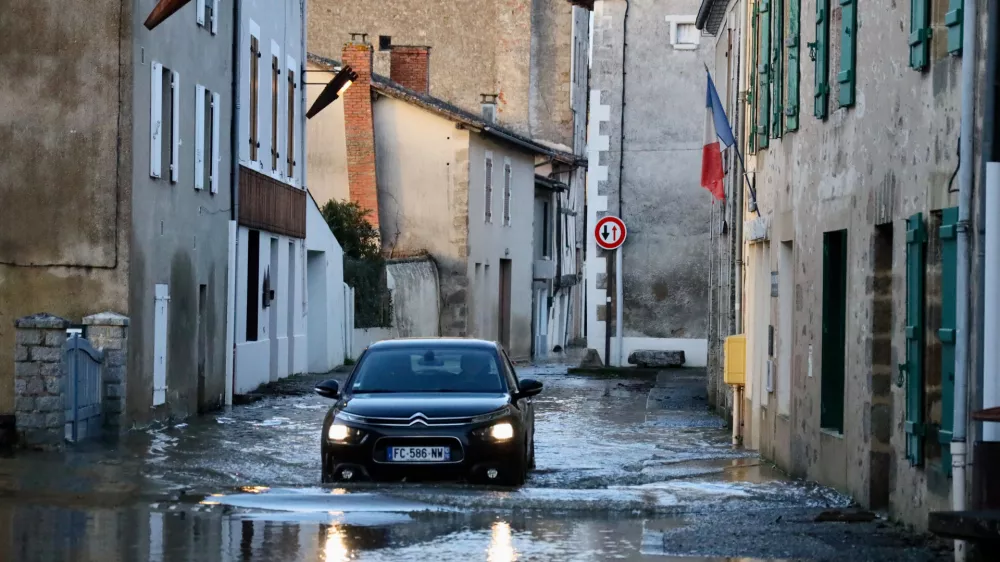 A car drives through a flooded street of Saint-Germain de Confolens as severe flooding hits western France amid storm Nils, Thursday, Feb. 12, 2026. (AP Photo/Yohan Bonnet)