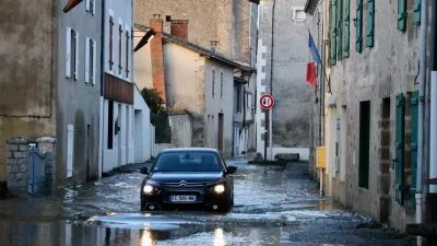 A car drives through a flooded street of Saint-Germain de Confolens as severe flooding hits western France amid storm Nils, Thursday, Feb. 12, 2026. (AP Photo/Yohan Bonnet)