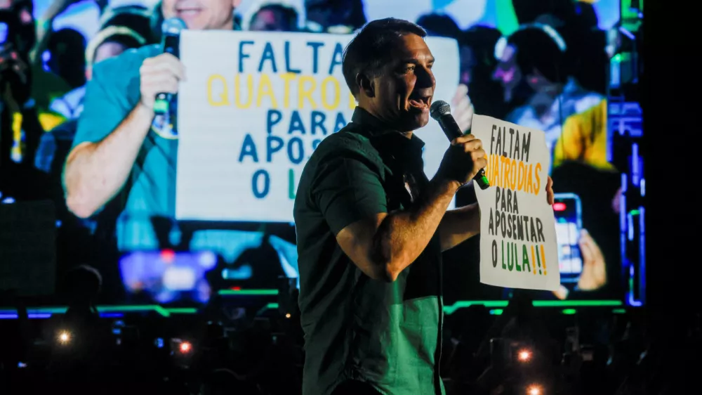 Presidential candidate Flavio Bolsonaro from the Liberal Party (PL) holds a placard reading "Four days left to retire Lula!!!", as he speaks on stage during a campaign event in Guarulhos, Brazil, October 21, 2026. REUTERS/Brian Snyder